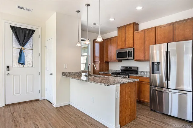 a kitchen with a refrigerator a microwave oven a sink and dishwasher with wooden floor