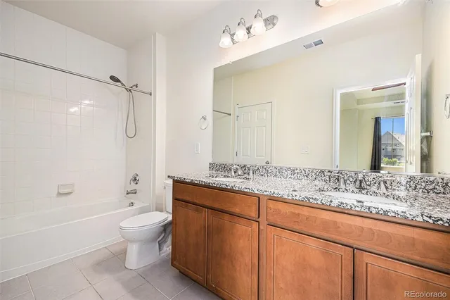 a bathroom with a granite countertop sink a toilet a mirror and bathtub
