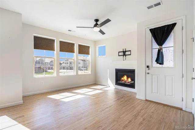 a view of a livingroom with a fireplace a ceiling fan and wooden floor
