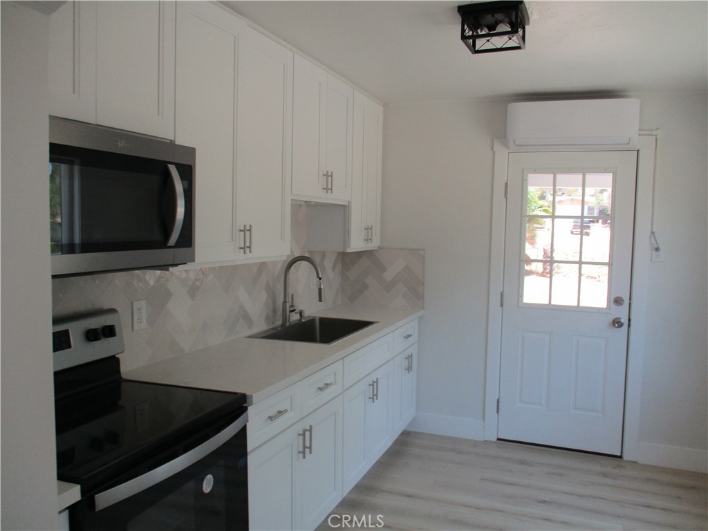 28584 Goetz Road Menifee, CA 92587 - Photo 6 of 10 a kitchen with stainless steel appliances a sink dishwasher a stove and a microwave oven on wooden floor