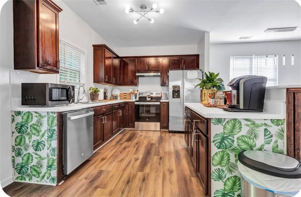 a kitchen with stainless steel appliances kitchen island granite countertop a sink a stove and a wooden cabinets