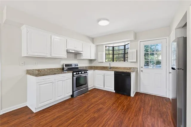 a kitchen with granite countertop wooden floors and white stainless steel appliances