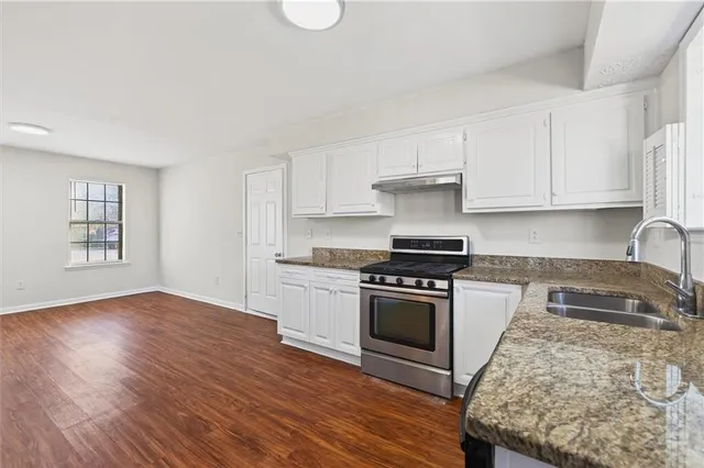 a kitchen with granite countertop a stove and a wooden floors