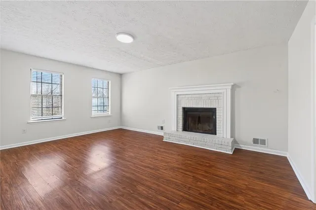 an empty room with wooden floor and fireplace