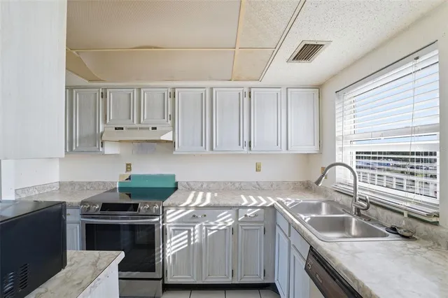 a kitchen with granite countertop a sink stove and cabinets