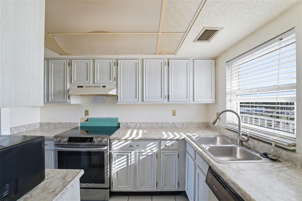 4939 Floramar Terrace, Unit 712 New Port Richey, FL 34652 - Photo 12 of 41 a kitchen with granite countertop a sink stove and cabinets