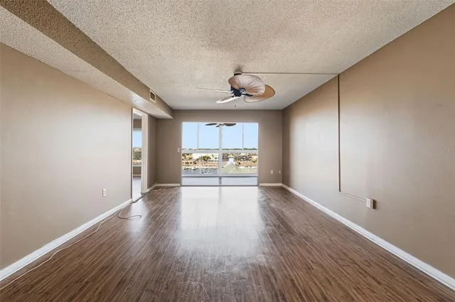a view of an empty room with a window and wooden floor