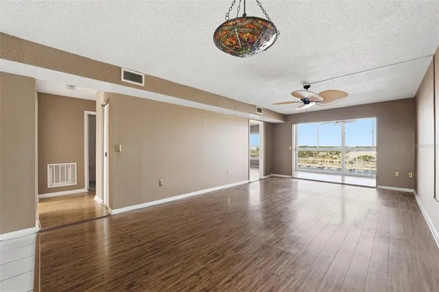 a view of an empty room with a window and wooden floor