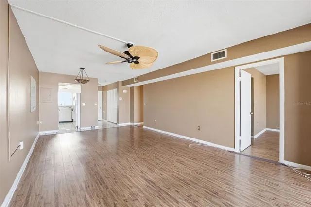 a view of an empty room with wooden floor and a window