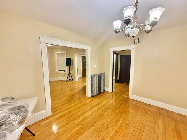 a view of a room with wooden floor and chandelier