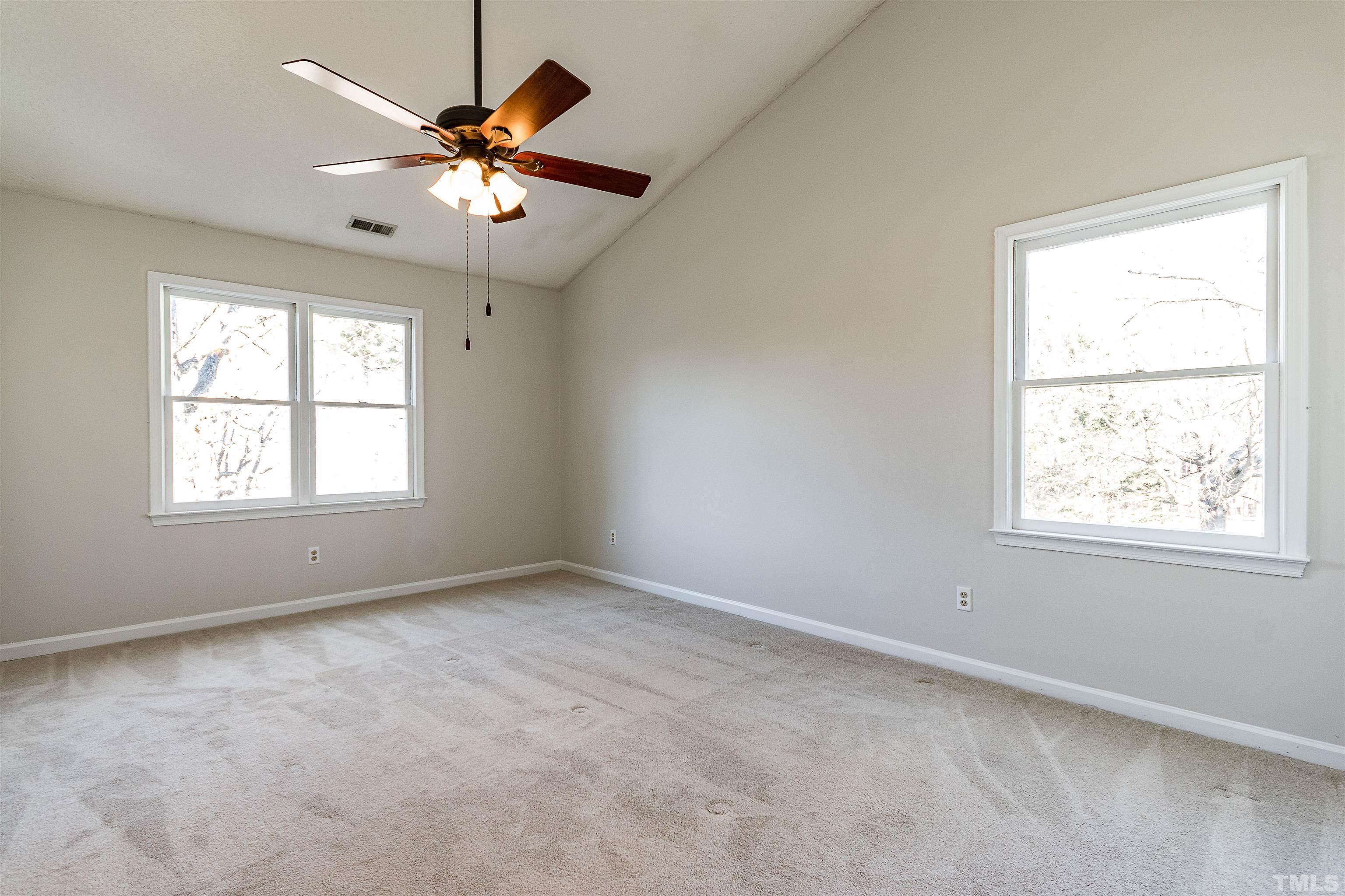 11801 Fairlie Place Raleigh, NC 27613 - Photo 15 of 32 an empty room with windows and chandelier fan