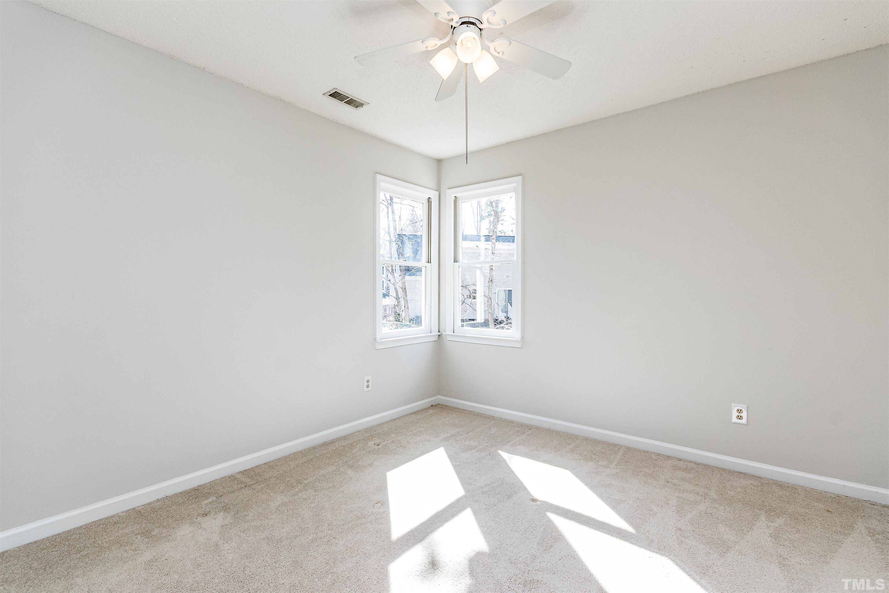 11801 Fairlie Place Raleigh, NC 27613 - Photo 17 of 32 an empty room with windows and chandelier fan