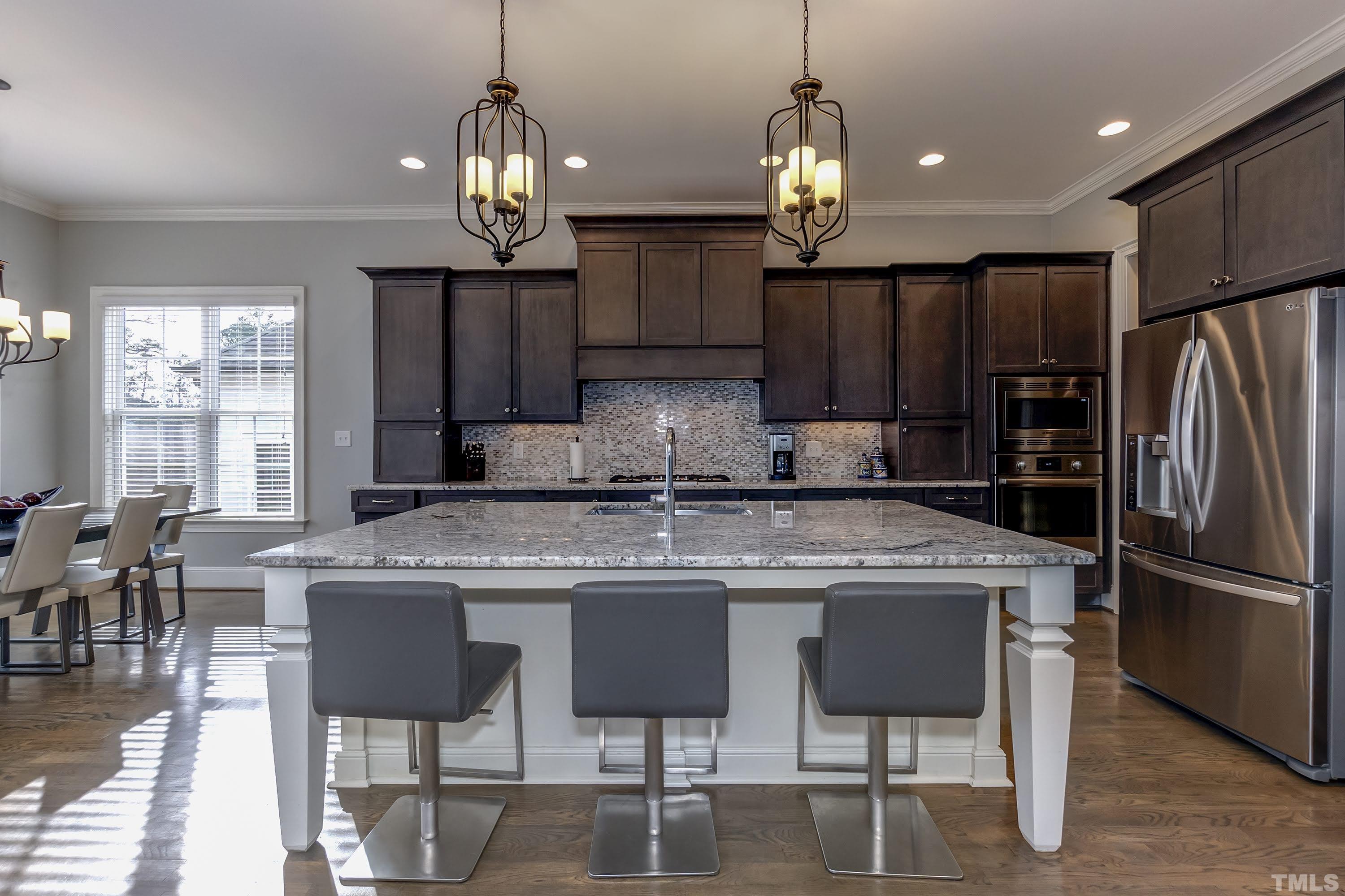 6418 Rosny Road Raleigh, NC 27613 - Photo 15 of 52 a kitchen with kitchen island granite countertop a center island a refrigerator cabinets and a dining table