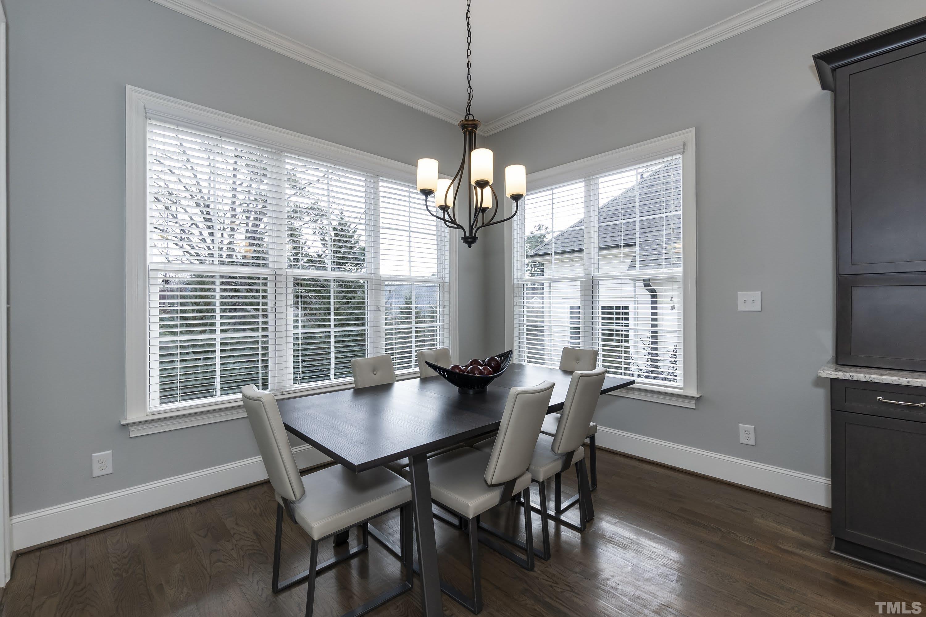 6418 Rosny Road Raleigh, NC 27613 - Photo 19 of 52 a dining room with wooden floor a chandelier a wooden table and chairs