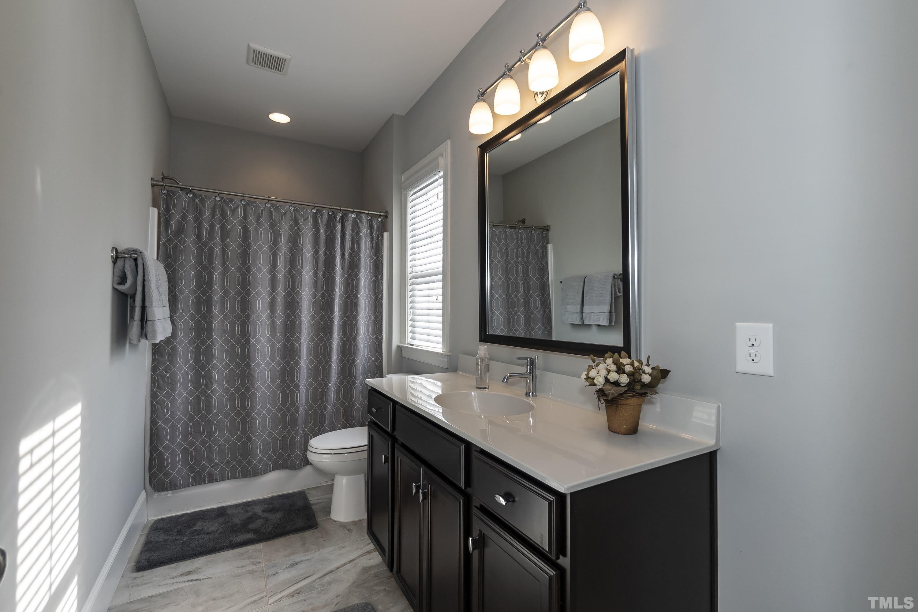 6418 Rosny Road Raleigh, NC 27613 - Photo 38 of 52 a bathroom with a sink vanity and a mirror