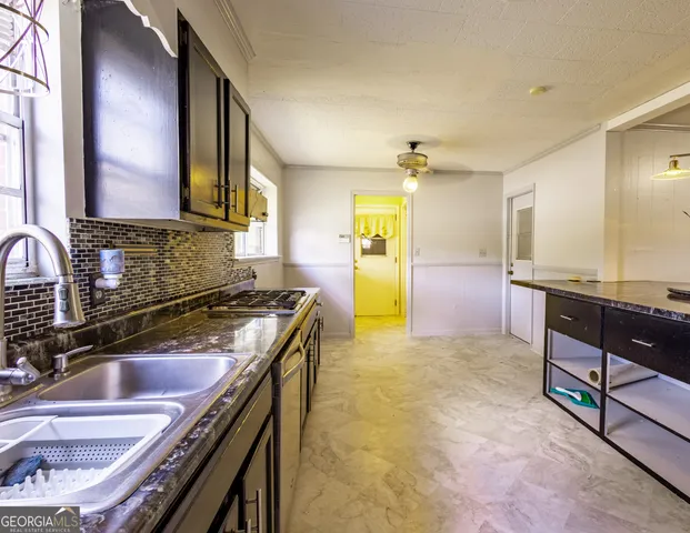 a kitchen with kitchen island granite countertop a sink stove and cabinets