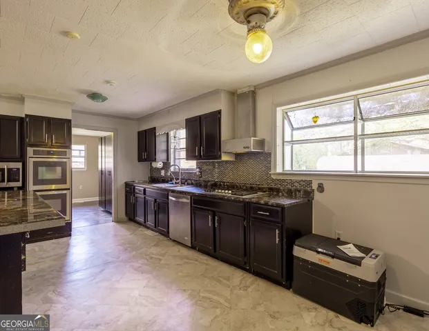a kitchen with stainless steel appliances granite countertop a stove top oven a sink a counter space and cabinets