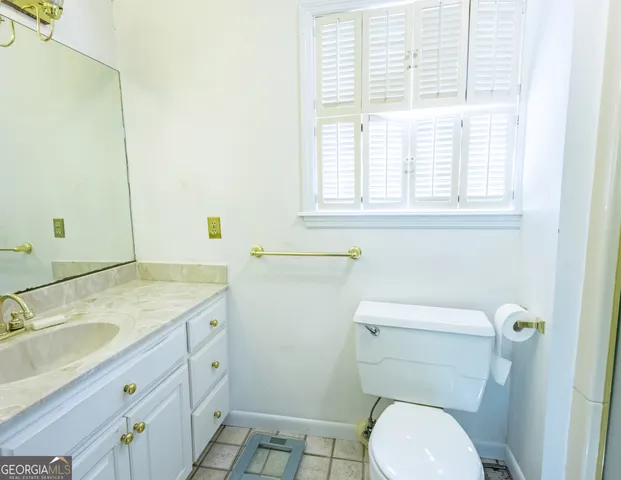 a bathroom with a granite countertop toilet a sink and a window