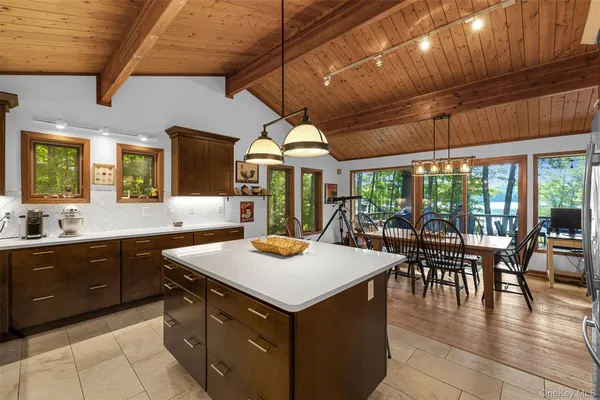 a kitchen with a stove a sink a dining table and chairs with a floor to ceiling window