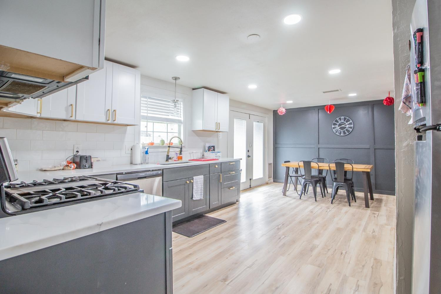 a kitchen with stainless steel appliances granite countertop a stove top oven a sink a dining table and chairs with wooden floor