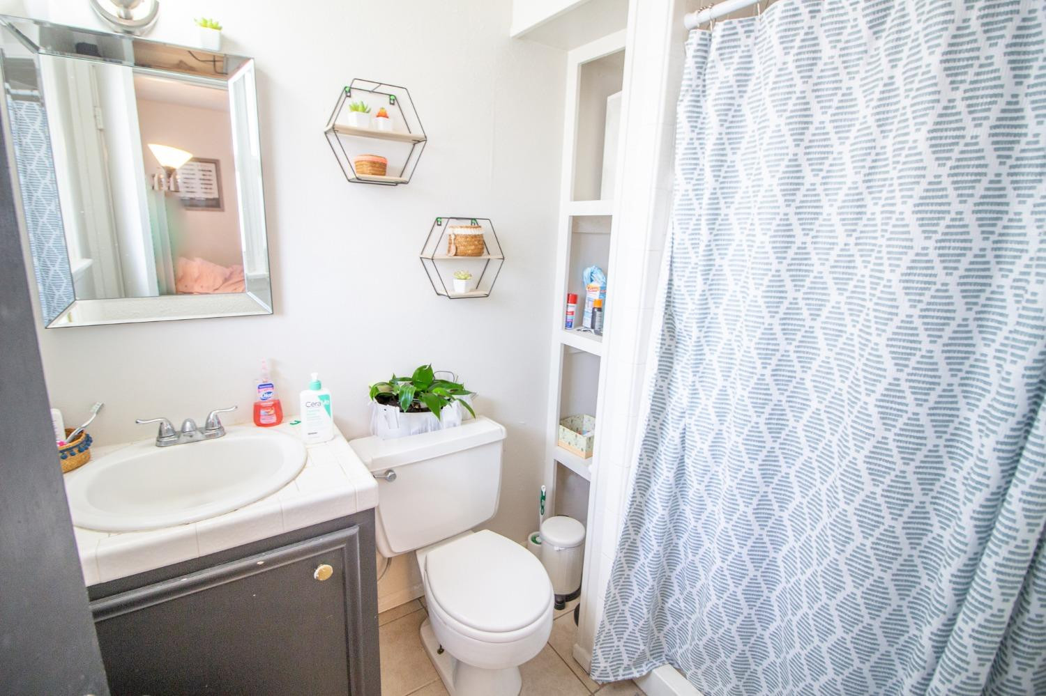 5411 32nd Street Lubbock, TX 79407 - Photo 14 of 22 a white toilet sitting next to a white sink and curtain