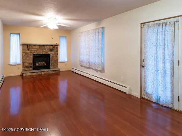 a view of an empty room with wooden floor fireplace and a window