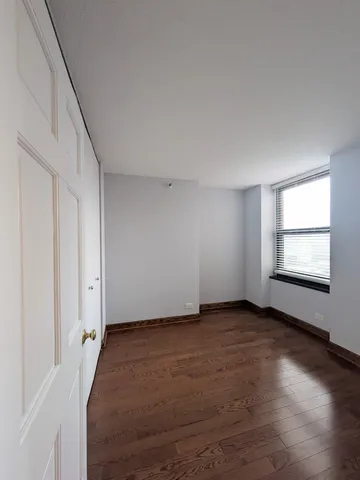 a view of empty room with wooden floor and closet