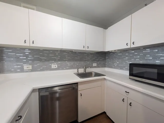 a kitchen with stainless steel appliances granite countertop a sink a stove and white cabinets