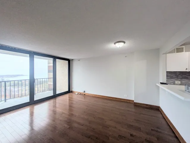 a view of an empty room with a window and wooden floor