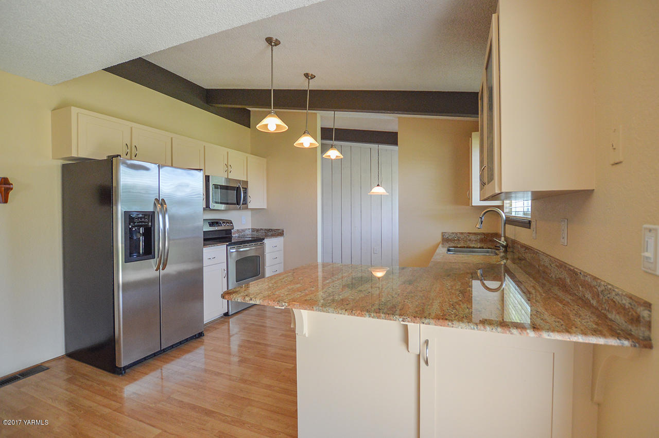 10820 Mieras Road Yakima, WA 98901 - Photo 4 of 21 a kitchen with granite countertop a refrigerator a sink and wooden floor