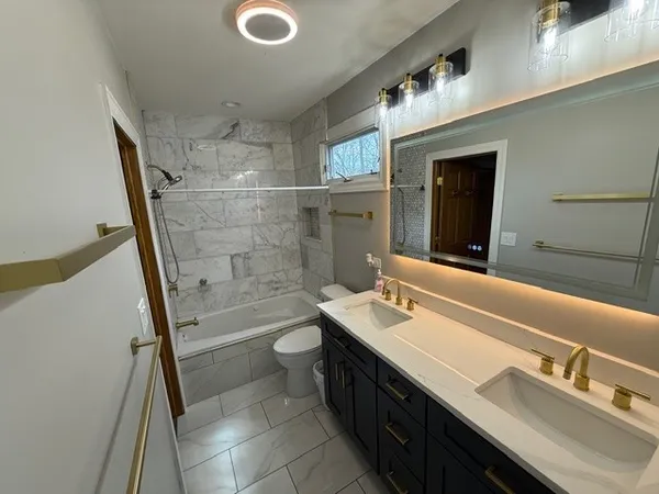 a bathroom with a sink a toilet a mirror and shower