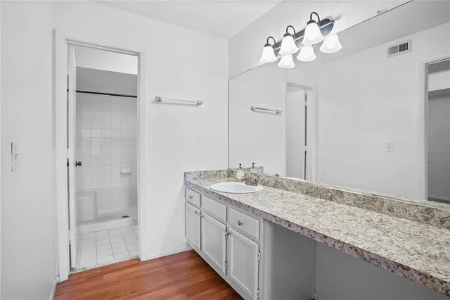 a bathroom with a granite countertop sink a mirror and a shower