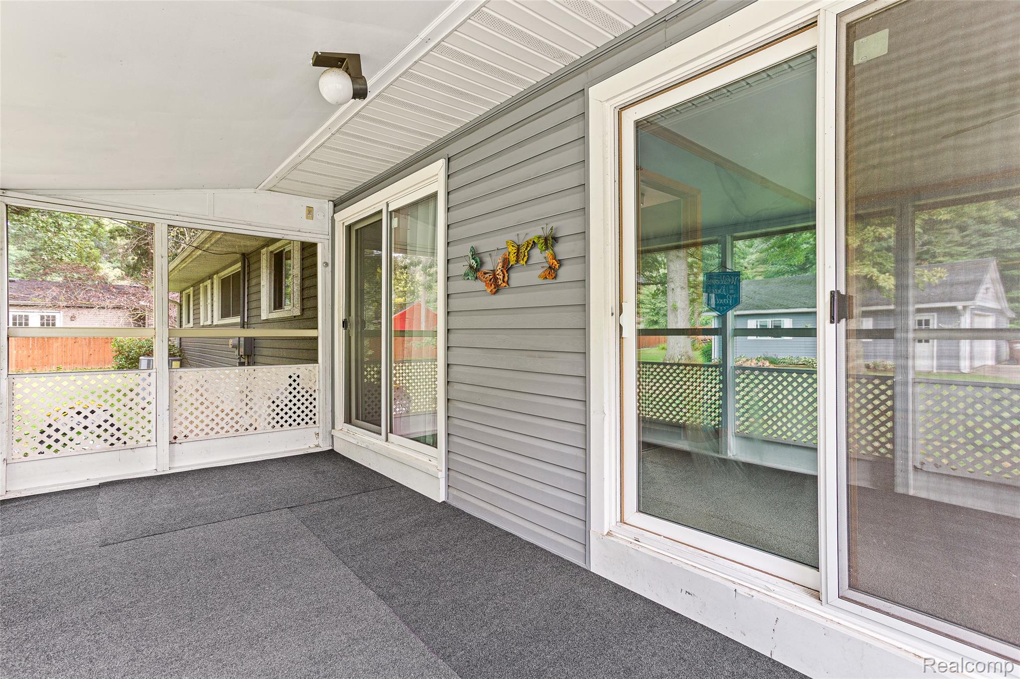 9561 Exeter Road Carleton, MI 48117 - Photo 34 of 46 Enclosed patio with full-height screening, gray outdoor carpeting, white lattice accents, and exterior siding