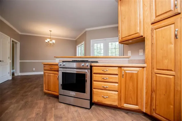 a kitchen with stainless steel appliances granite countertop wooden cabinets a stove a sink and a large window