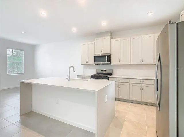 a kitchen with cabinets appliances a sink and a window