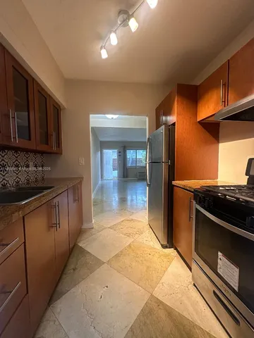 a kitchen with stainless steel appliances granite countertop a refrigerator and a stove top oven