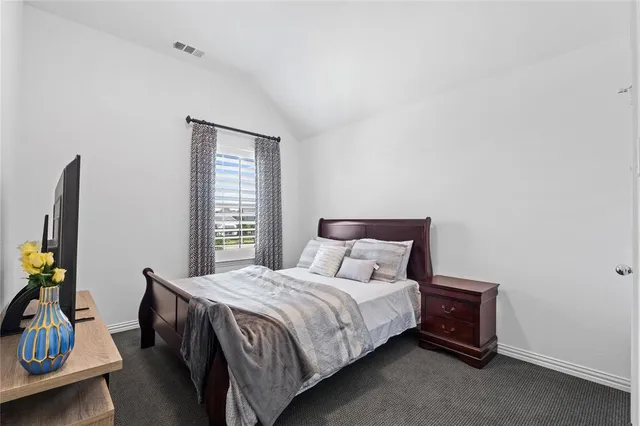 a bedroom with a bed a flat screen tv and a window