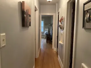 a view of a hallway with wooden floor and a bathroom