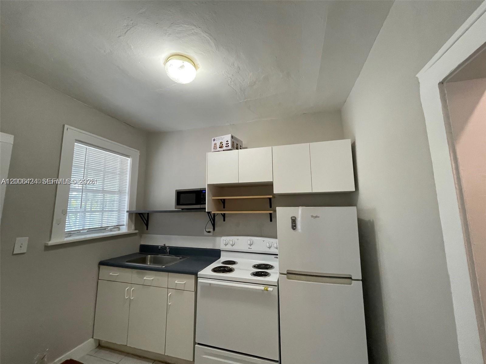 3364 Southwest 2nd Street, Unit 4 Miami, FL 33135 - Photo 11 of 14 a kitchen with a refrigerator a stove a microwave a sink and cabinets