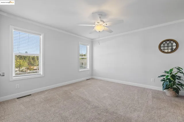 an empty room with windows and ceiling fan