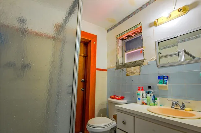 a bathroom with a sink a toilet a mirror and shower