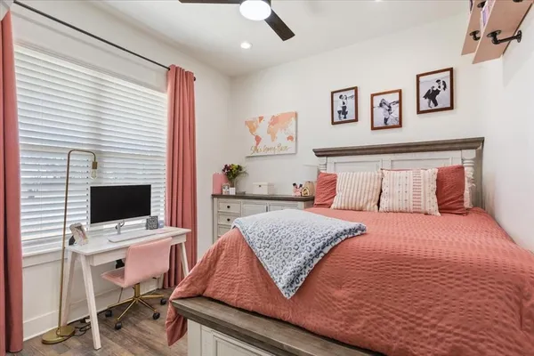 a bedroom with a bed and a computer on a desk next to a window