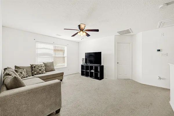 a living room with furniture a ceiling fan and a flat screen tv