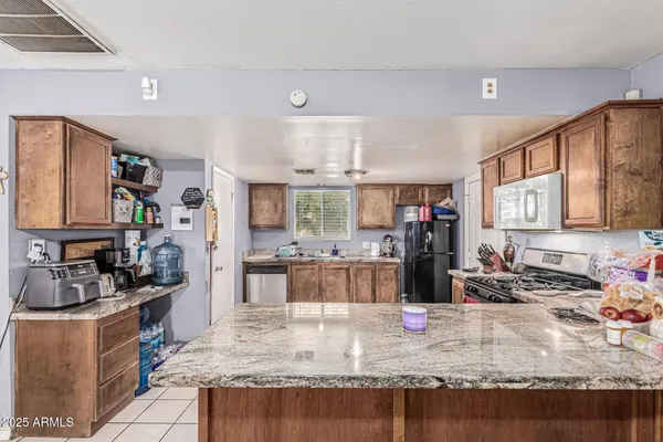 a kitchen with stainless steel appliances granite countertop a stove top oven a sink dishwasher and a refrigerator