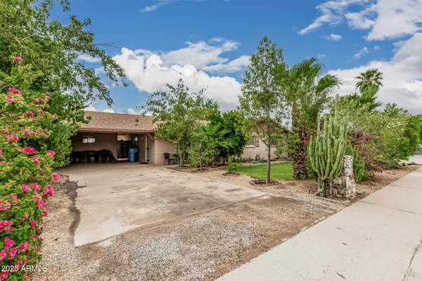 a white house that has a small yard and trees in the background