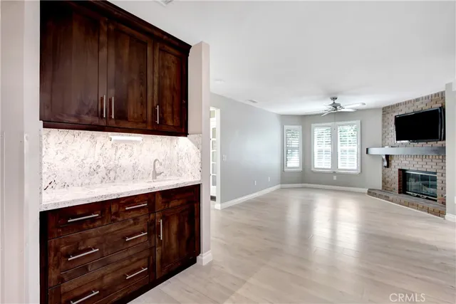 an empty room with wooden floor and way to kitchen