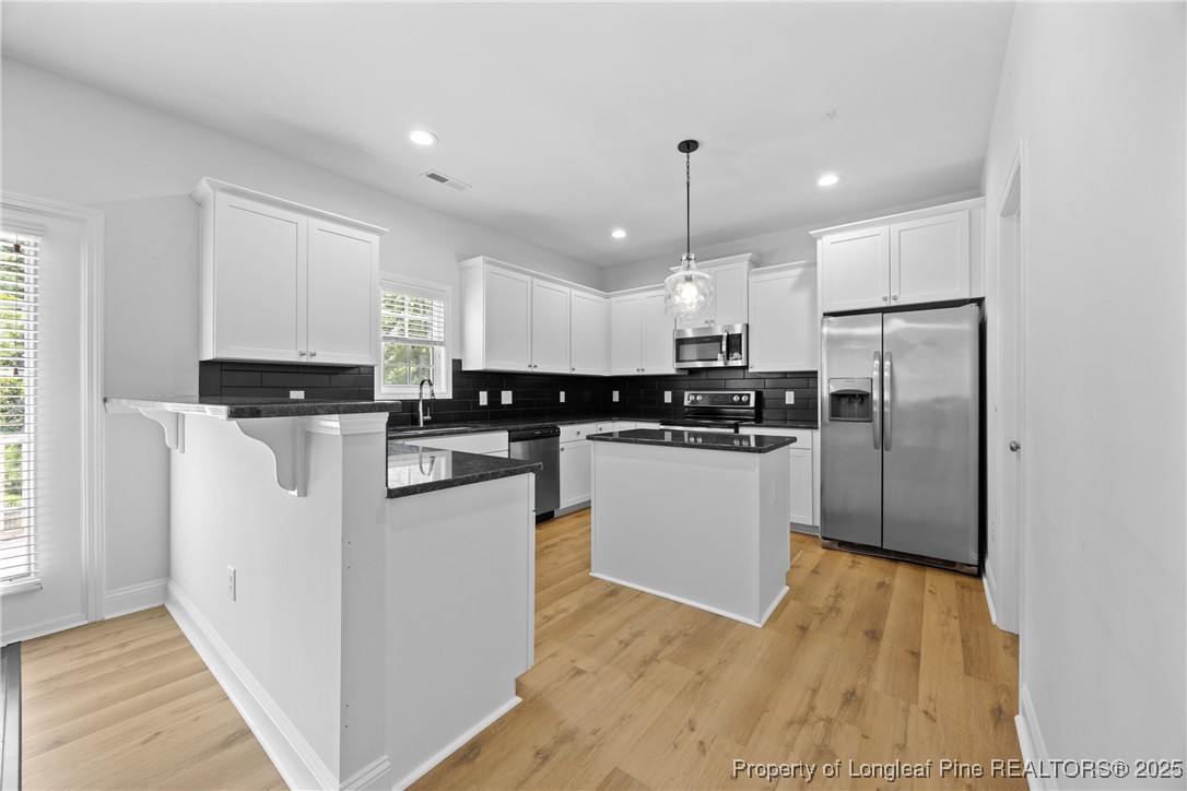 156 Silk Oak Drive Bunnlevel, NC 28323 - Photo 12 of 50 a kitchen with stainless steel appliances granite countertop a refrigerator a sink a stove and white cabinets
