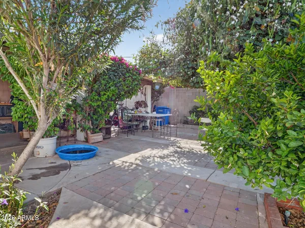a view of a patio with table and chairs potted plants and large tree