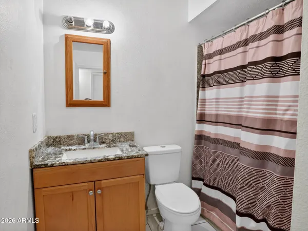 a bathroom with a granite countertop toilet sink and mirror