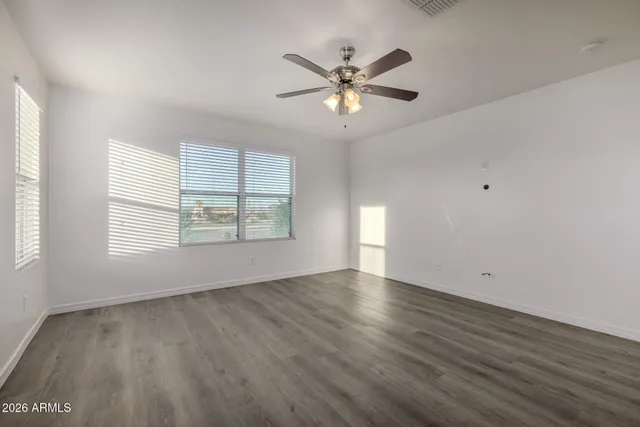 an empty room with windows and chandelier fan